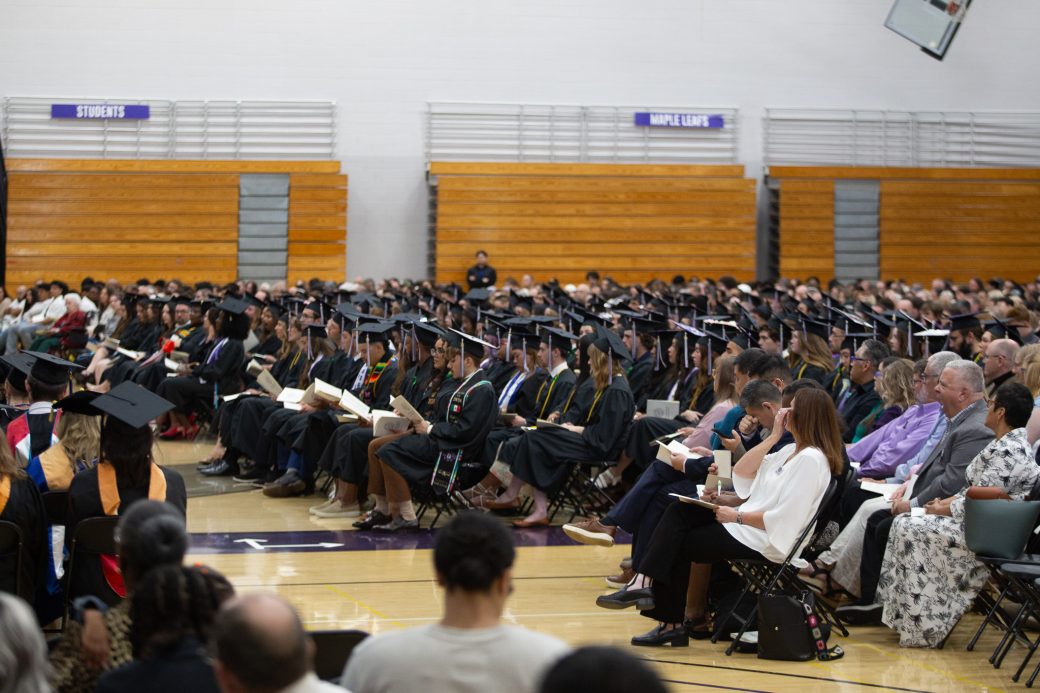 Graduates seated together as audience members watch from behind during the commencement ceremony at Goshen College