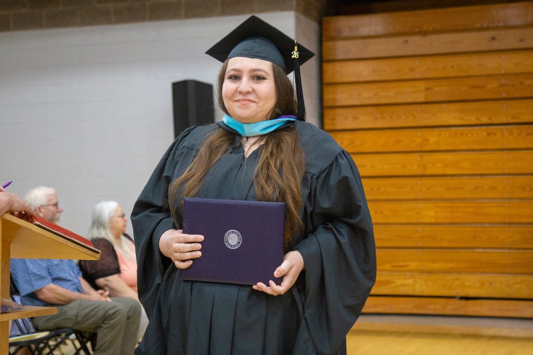 Graduate holding diploma and smiling after ceremony