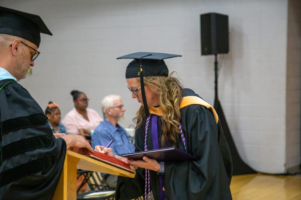 Graduate signing book after receiving diploma