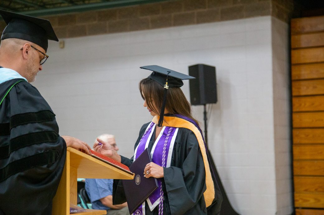 Graduate signs book after receiving diploma
