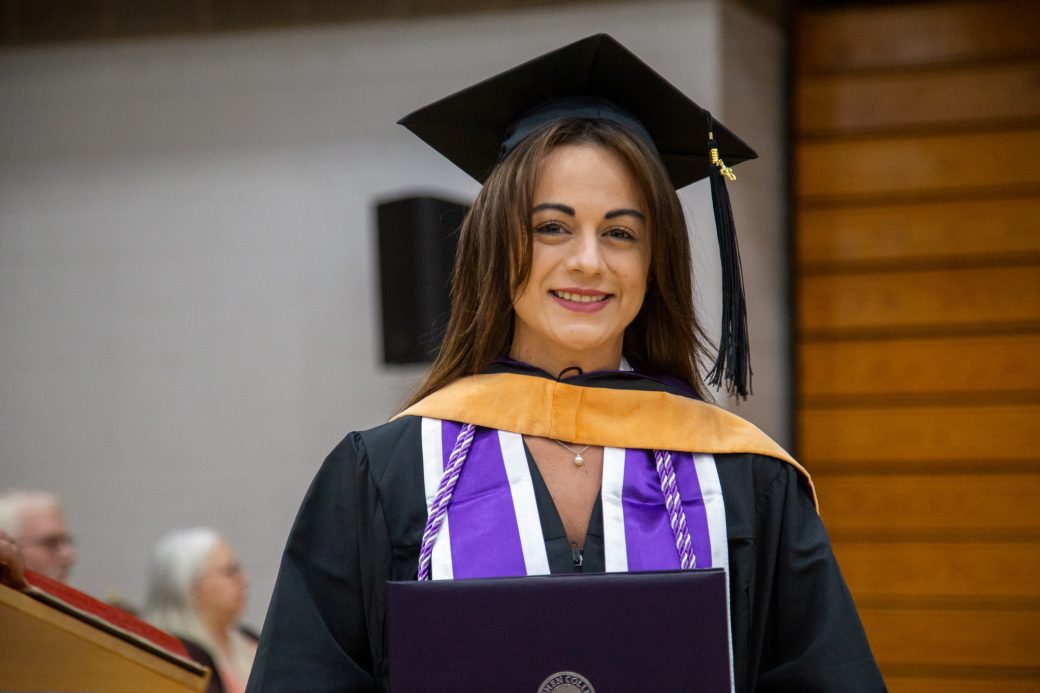Graduate holding diploma and smiling with pride