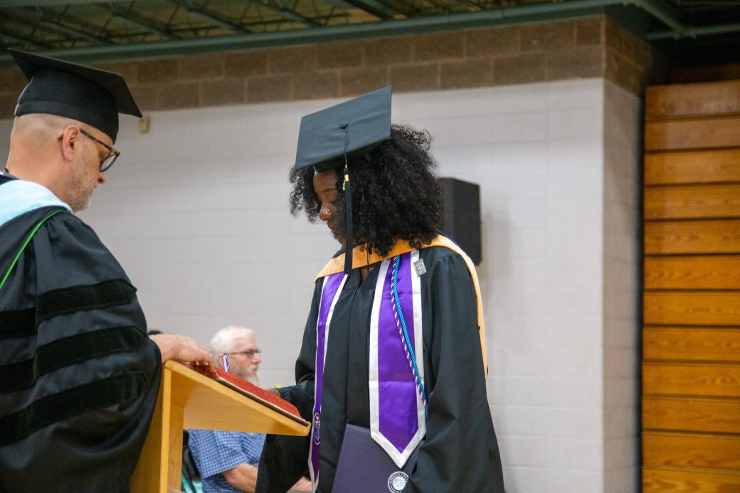 Graduate signing commemorative book after receiving diploma