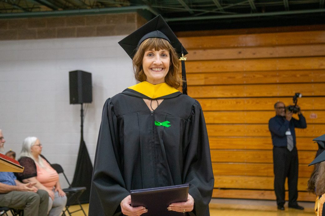 Graduate smiling and holding diploma after ceremony