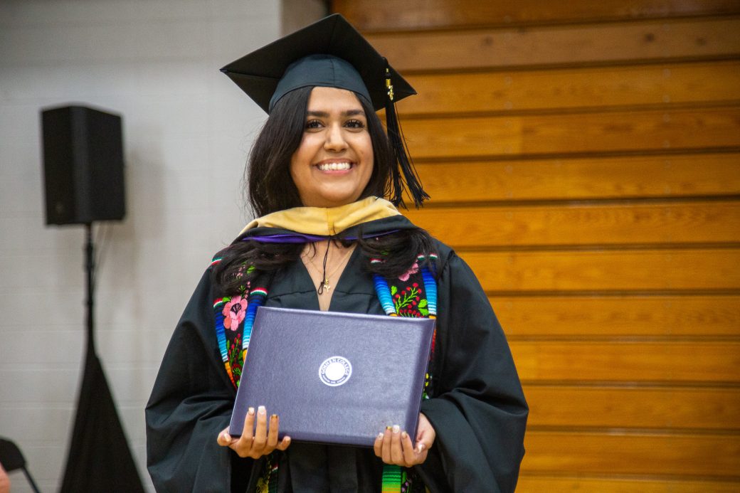 Graduate posing with diploma following the stage