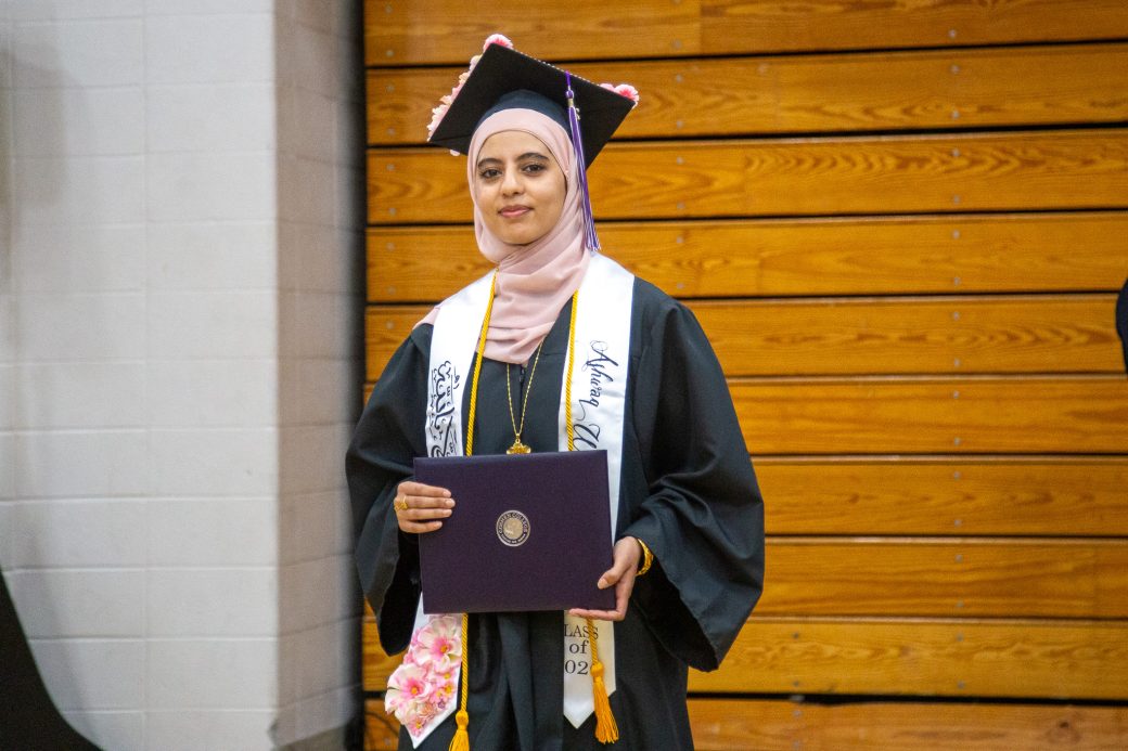 Graduate smiling while holding diploma in both hands