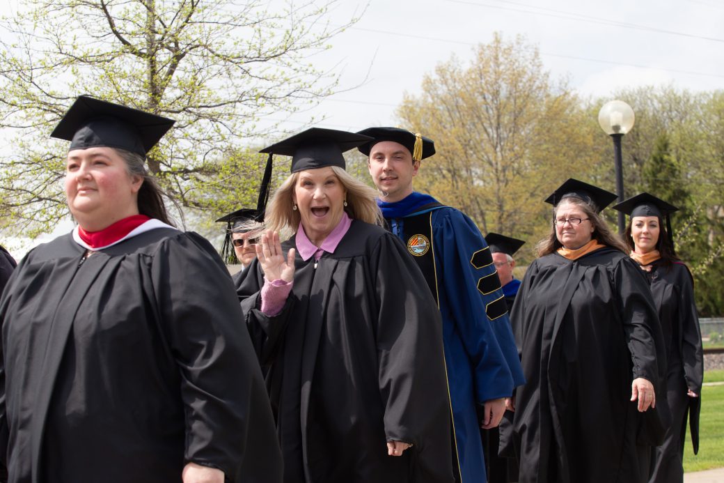 Angela Sienko waving for photo in graduation processional
