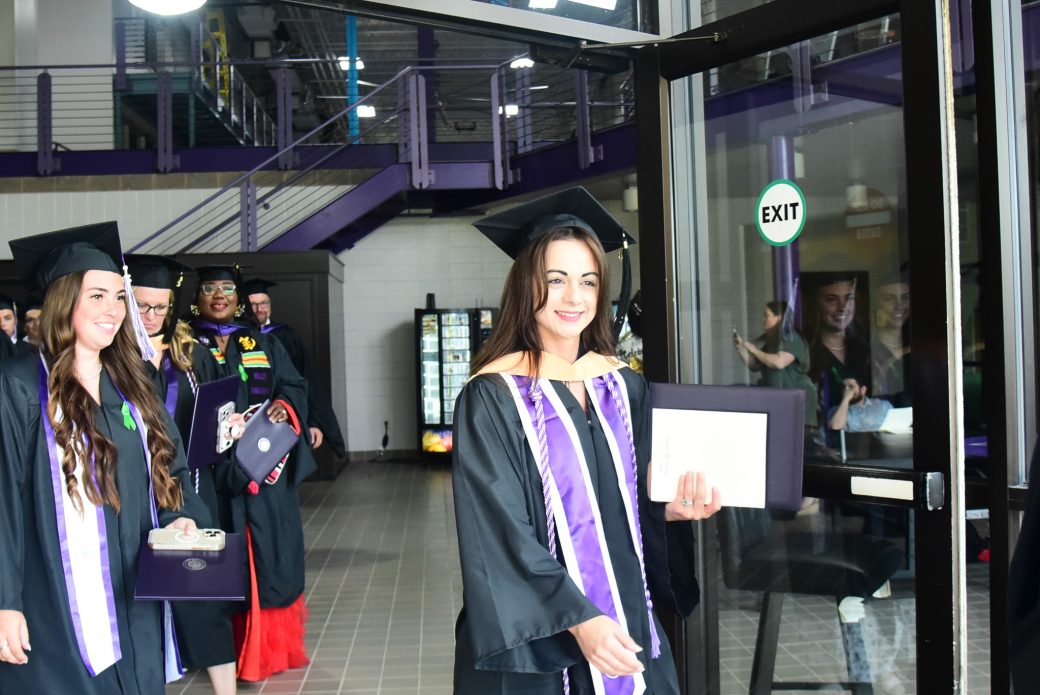 Students walking through doorway toward the outdoors after commencement