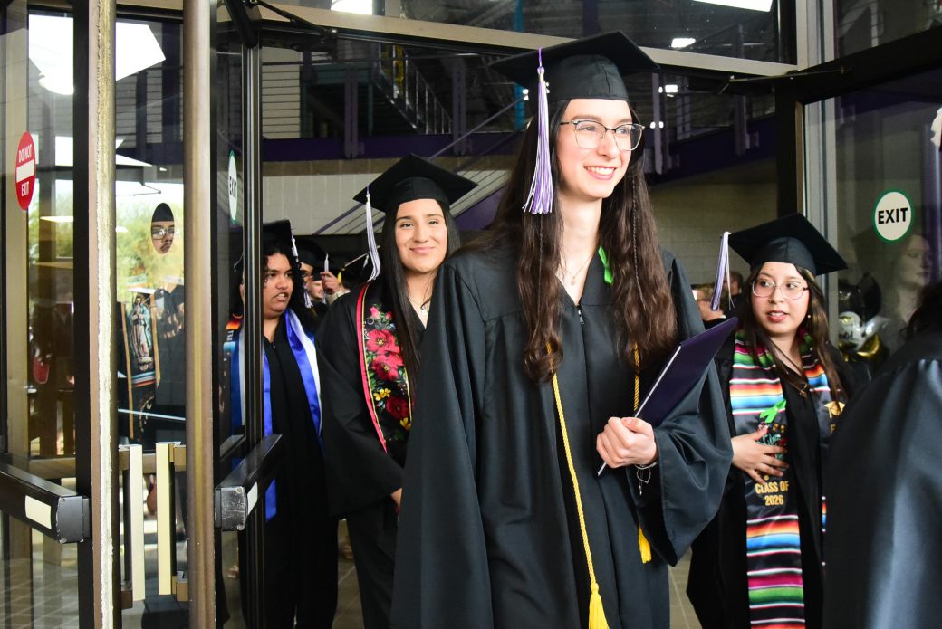 Graduates passing through doorway into daylight after ceremony