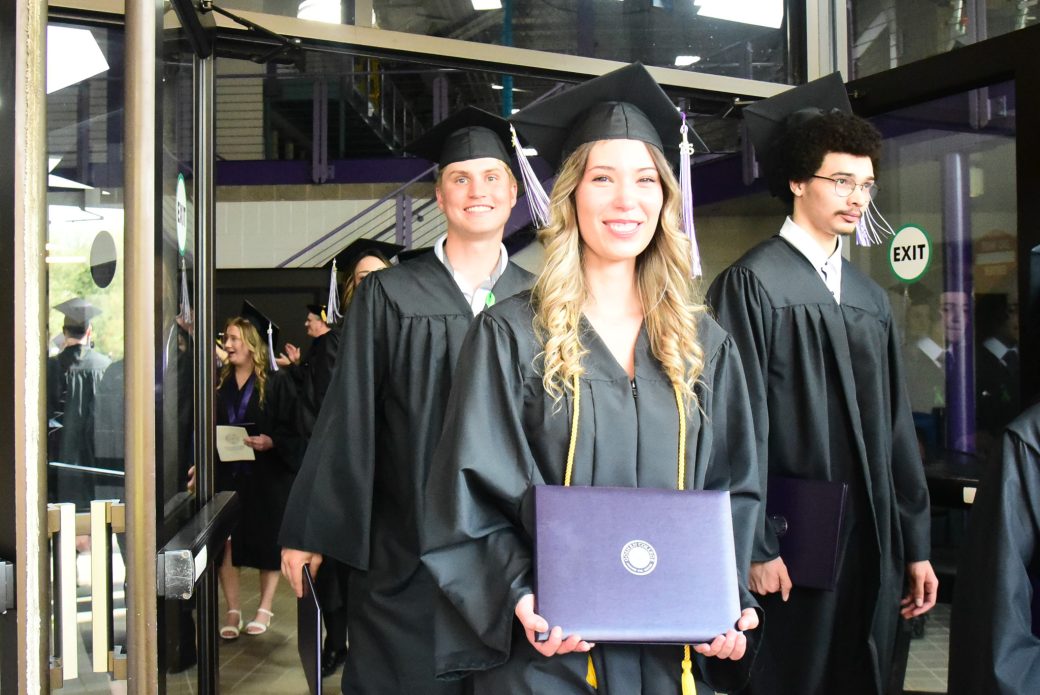 Graduates walking through open doors as they leave ceremony