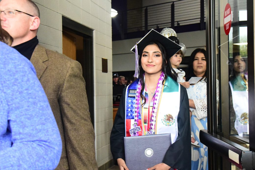 Students moving through doorway toward outdoor area after graduation