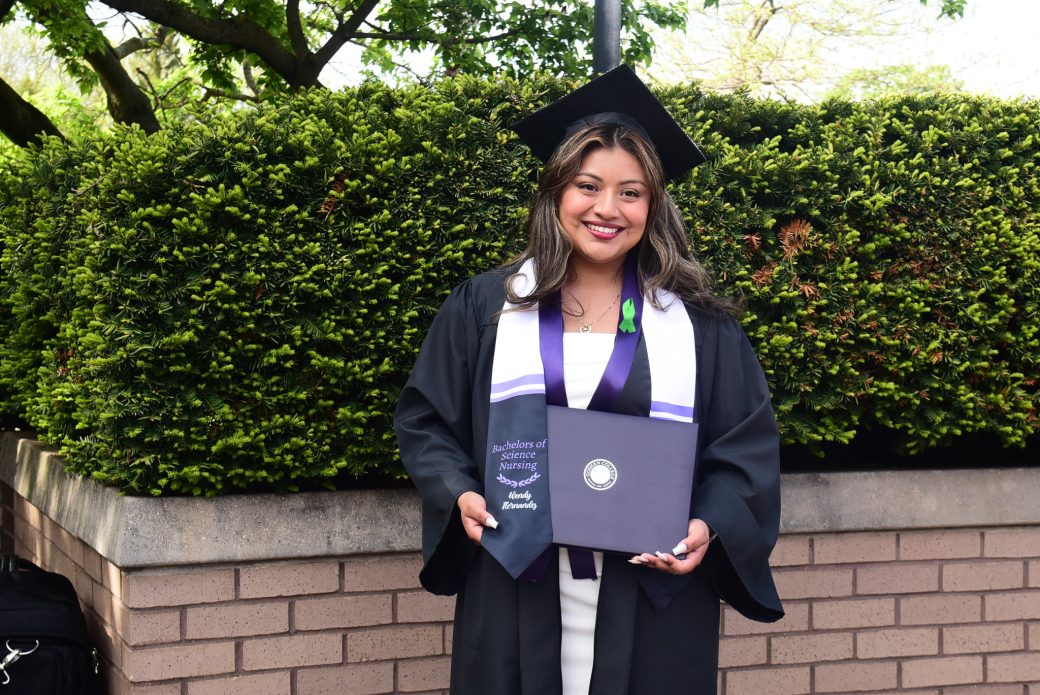 Graduate holding diploma and smiling outdoors