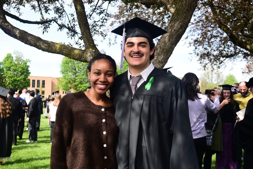 Graduate posed outside under tree with friend