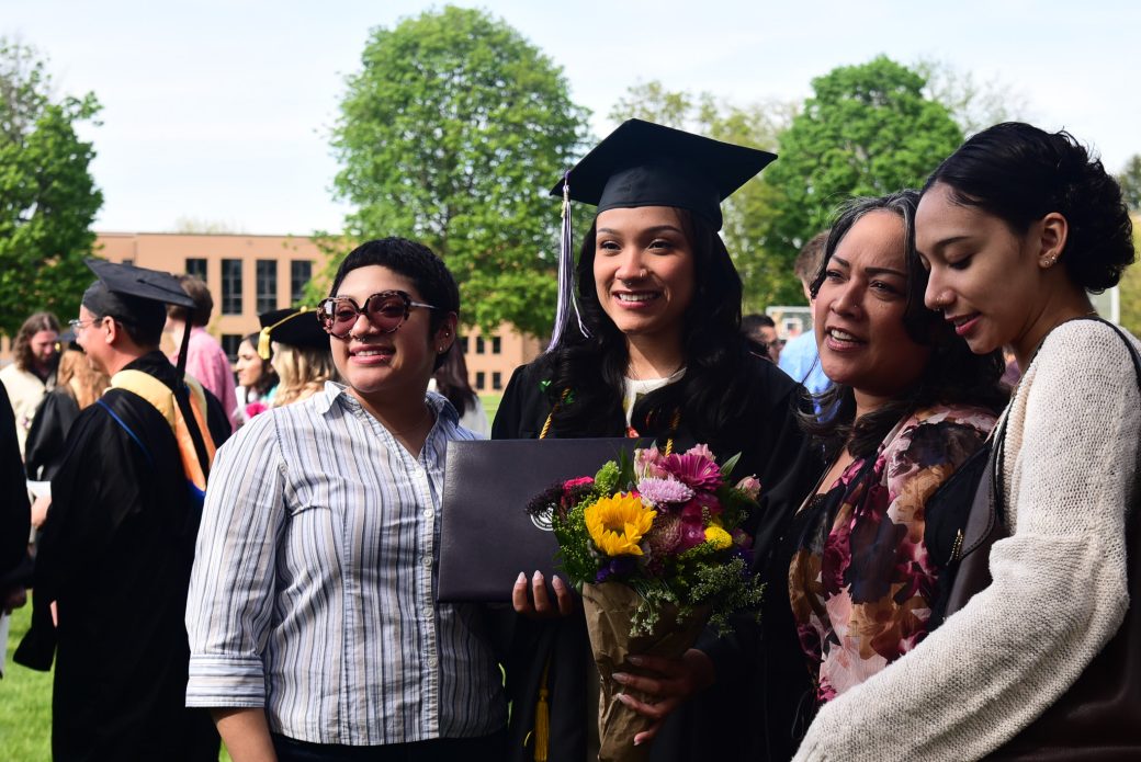 Graduate holding flowers with family