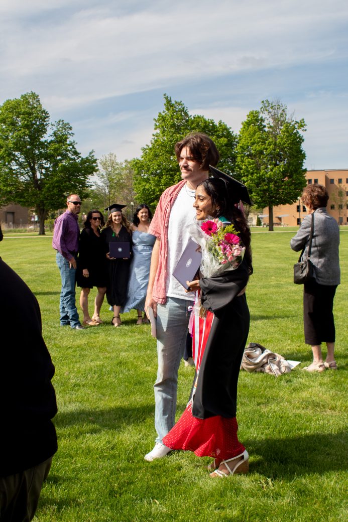 Graduate posed with friend and flowers