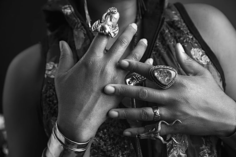 black and white photo of hands with lots of jewelry on them