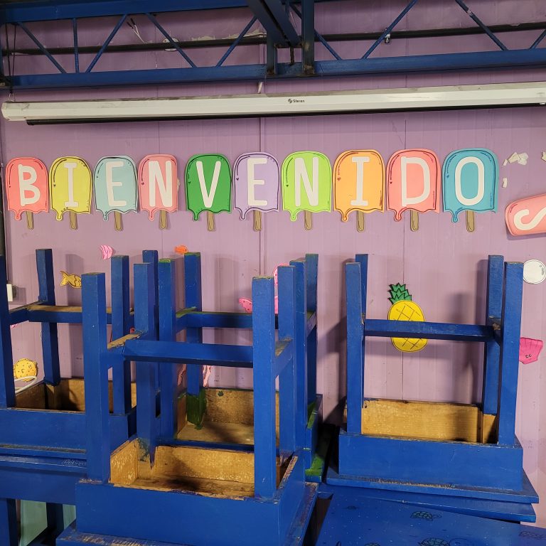 Letters spell out welcome on a light purple background above a series of upturned chairs.