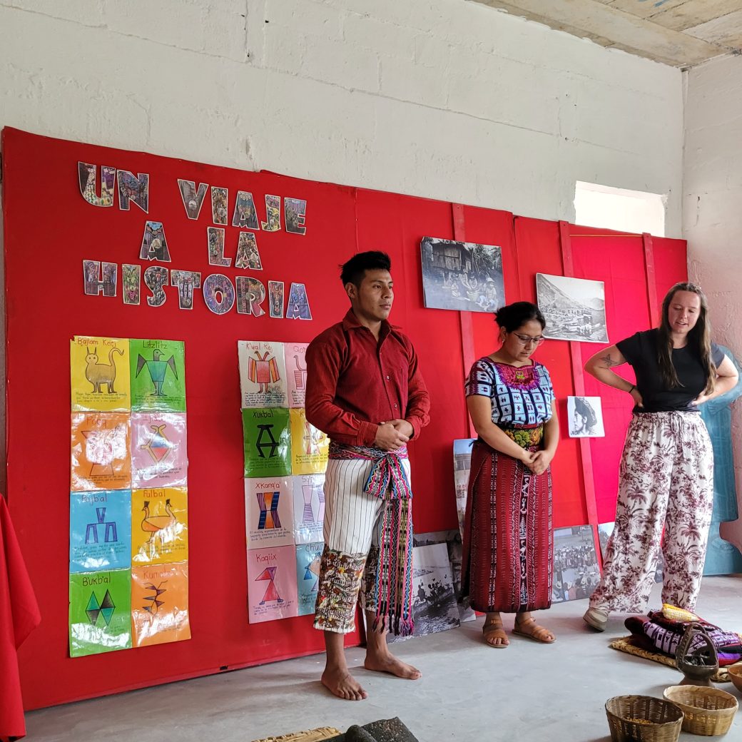 Three people standing before a red background.
