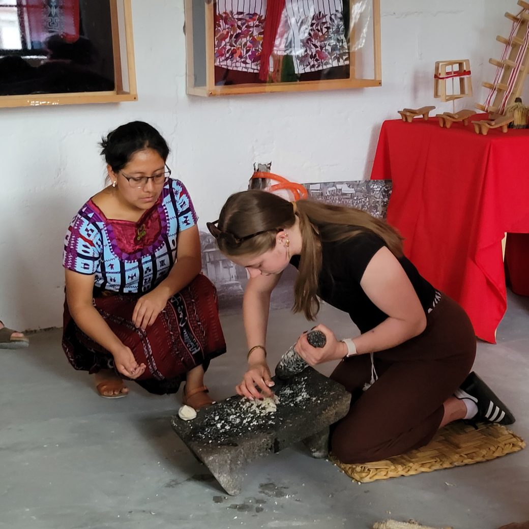 A person kneeling and grind corn with a stone.