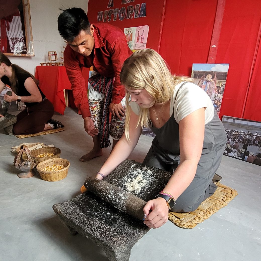 A person kneeling and grind corn with a stone.