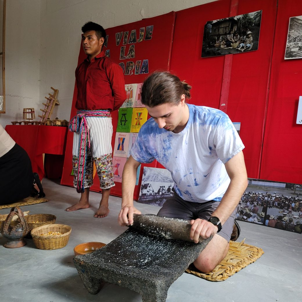 A person kneeling and grind corn with a stone.