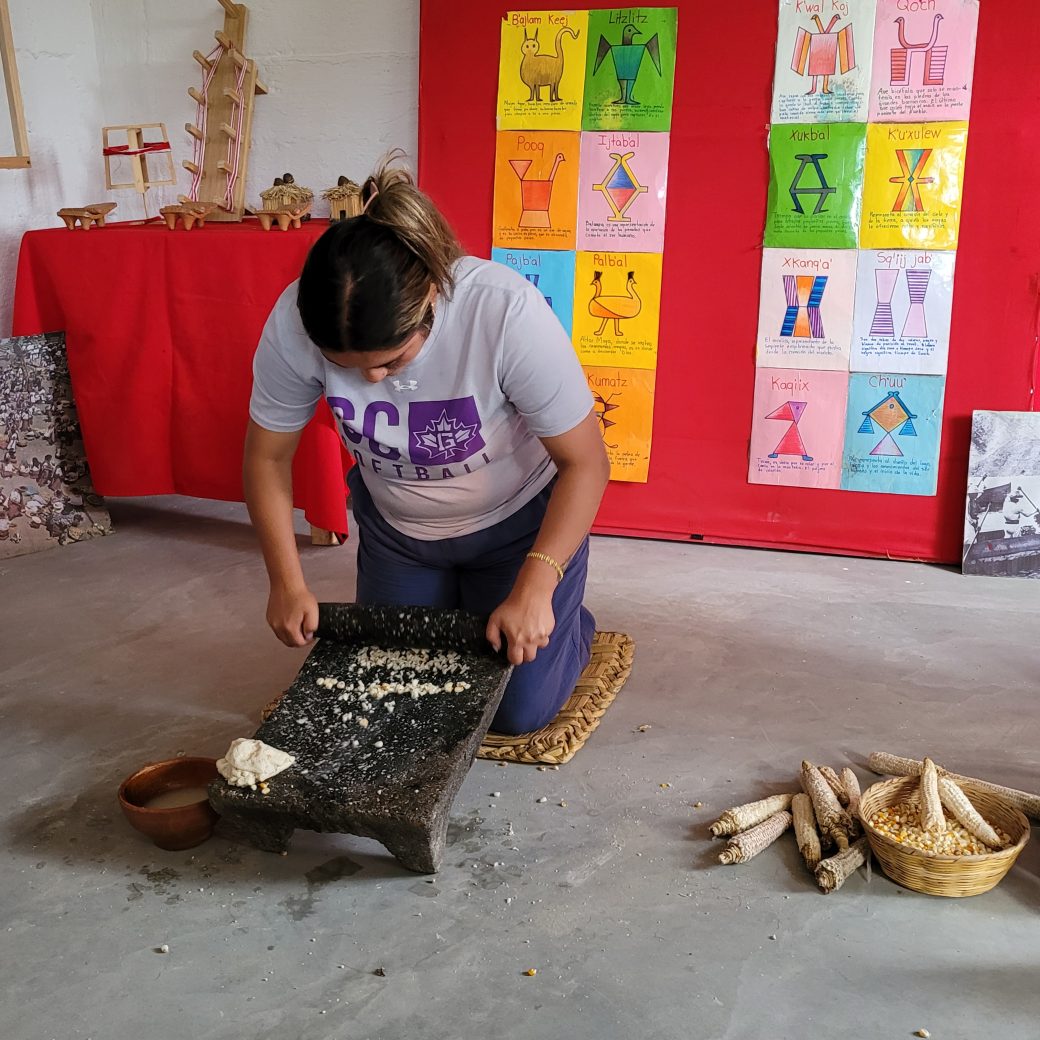 A person kneeling and grind corn with a stone.