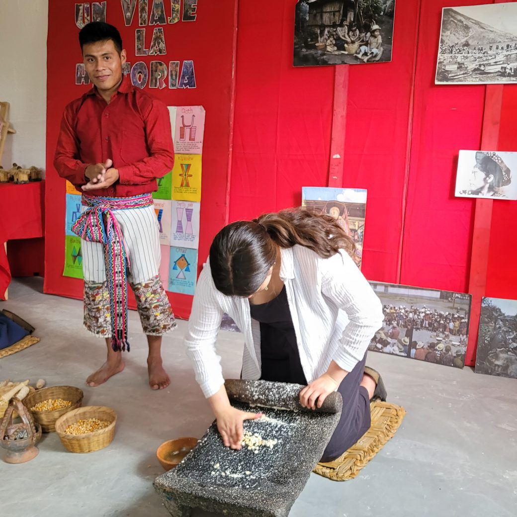A person kneeling and grind corn with a stone.