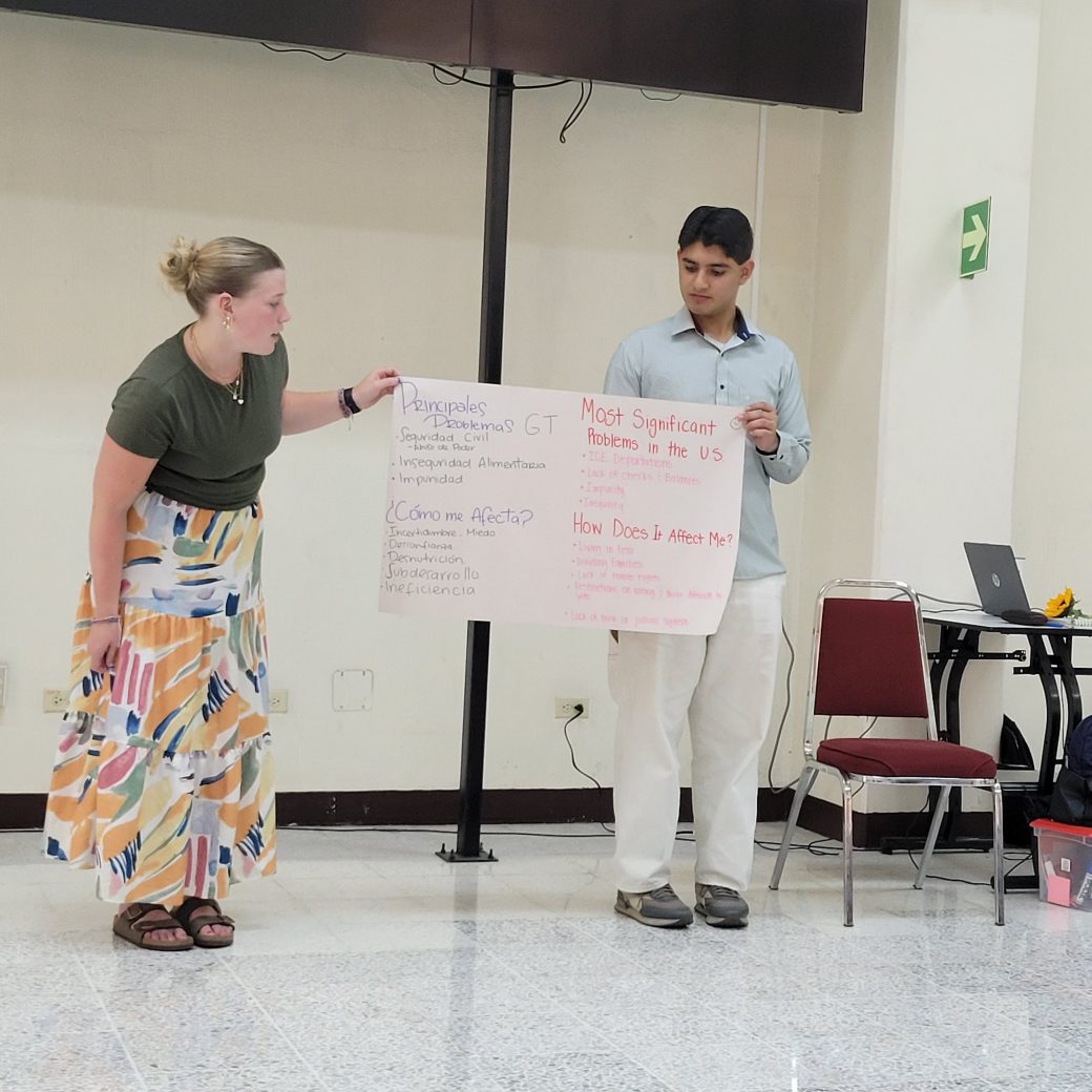 Two people holding a large paper with handwritten notes.