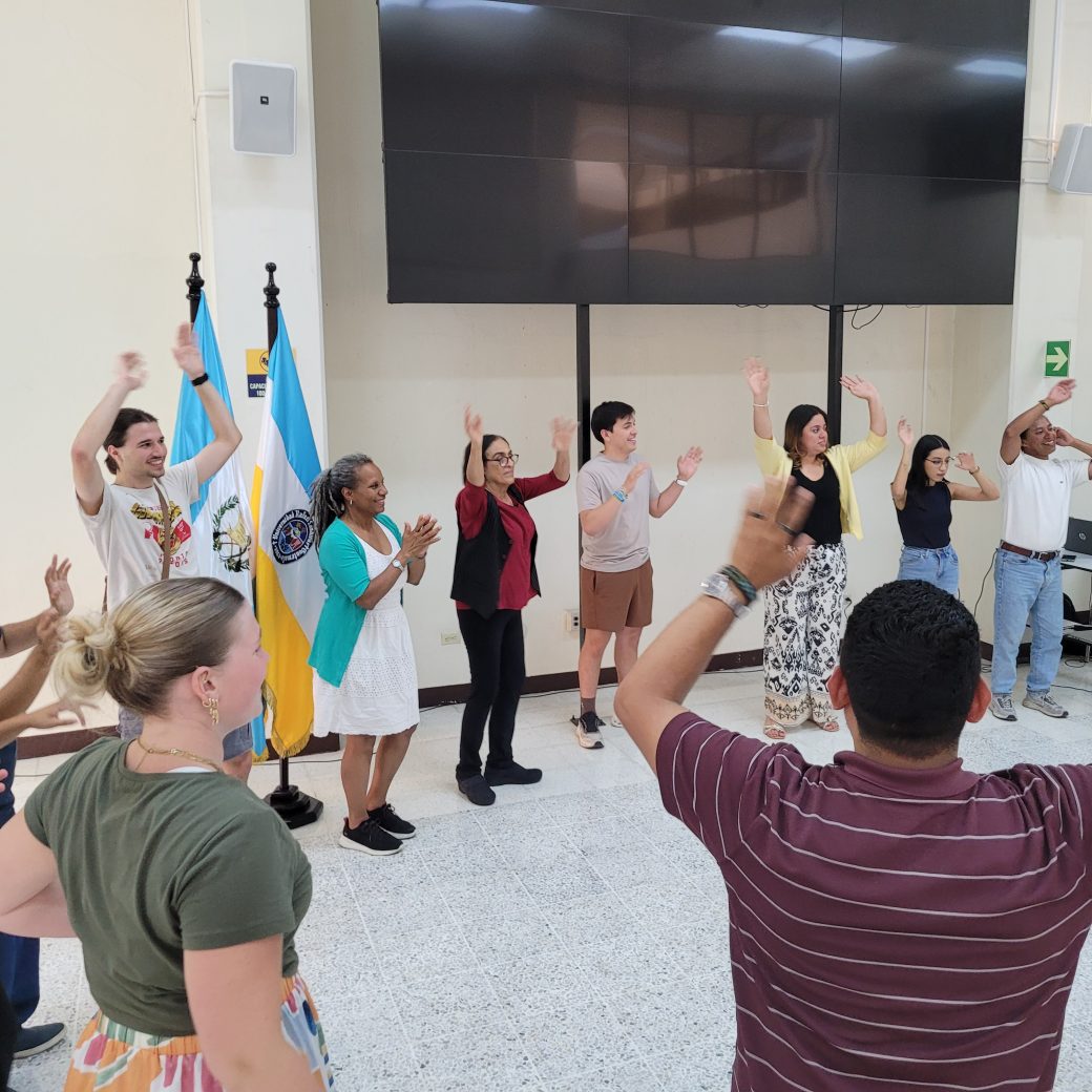 A large group of young people, standing in a circle with their hands raised.