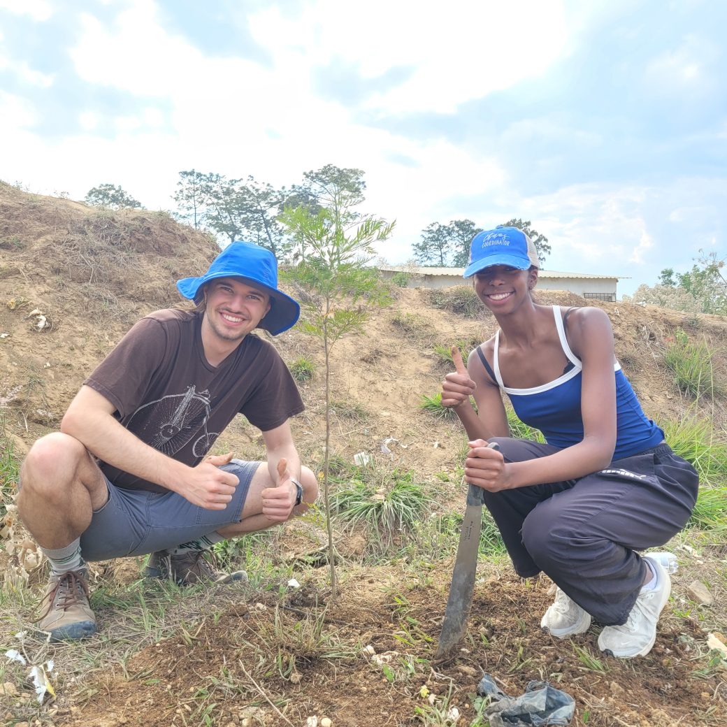 Two people next to a tree sapling.
