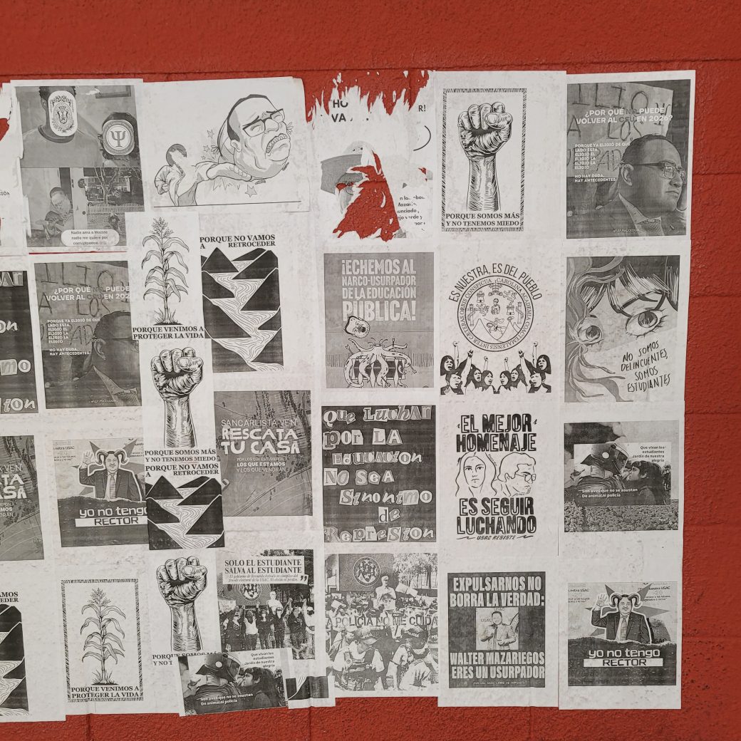A series of black and white posts pasted on a red wall.
