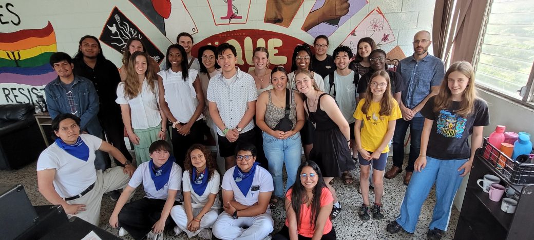 A large group of people pose in front of a mural
