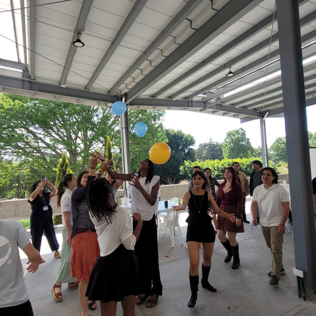 A group of people raising their hands towards balloons in the air.