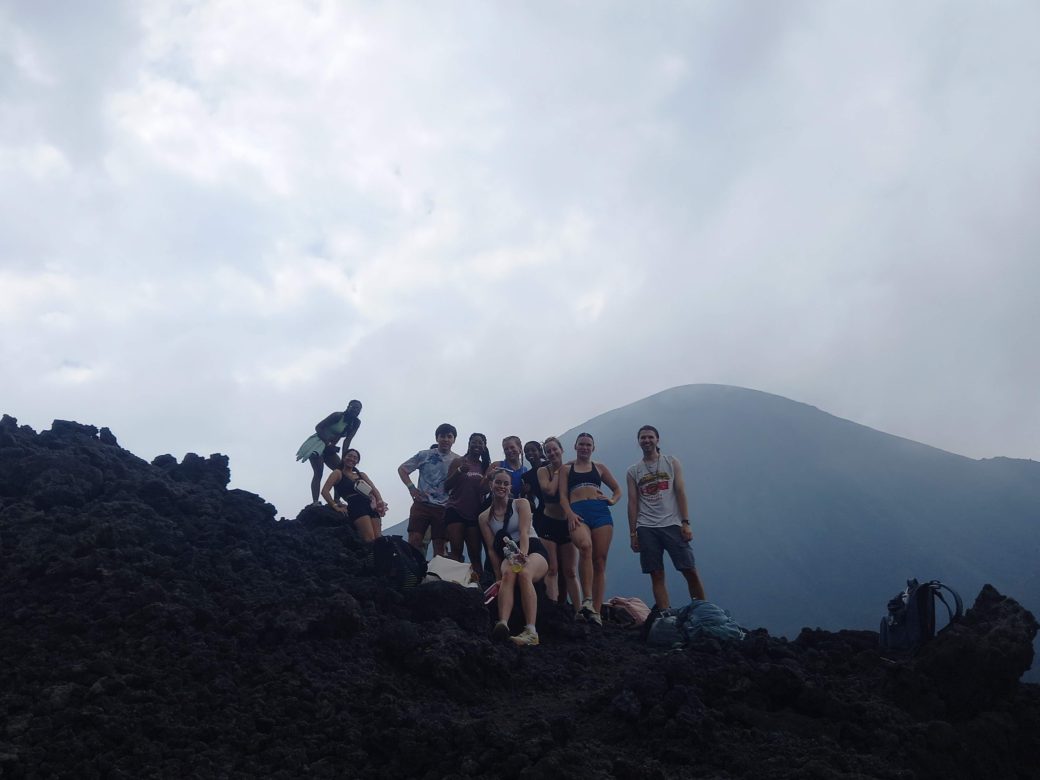 A group of people pose by a mountaintop.