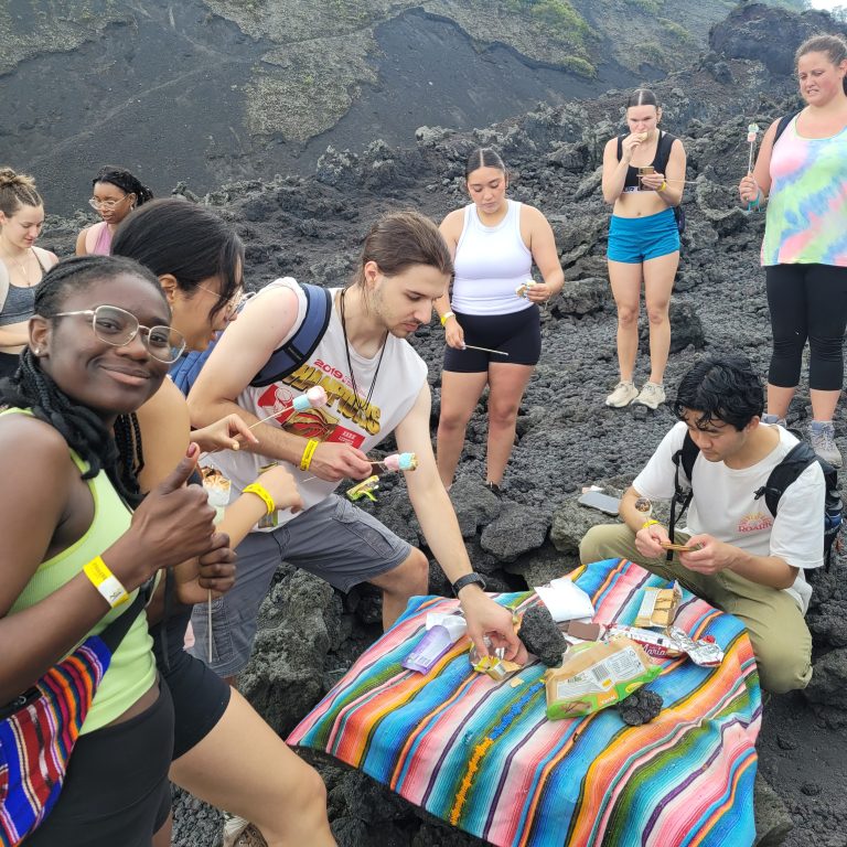 A group of people on a rocky mountainside, eating crackers, marshmallows, and chocolate