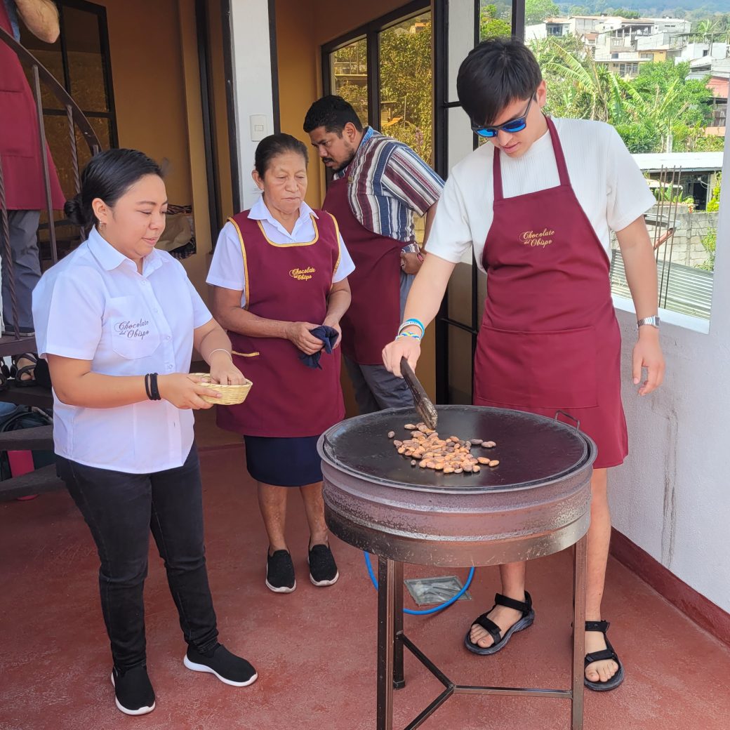 A person standing over a hot roasting pan while wearing an apron.