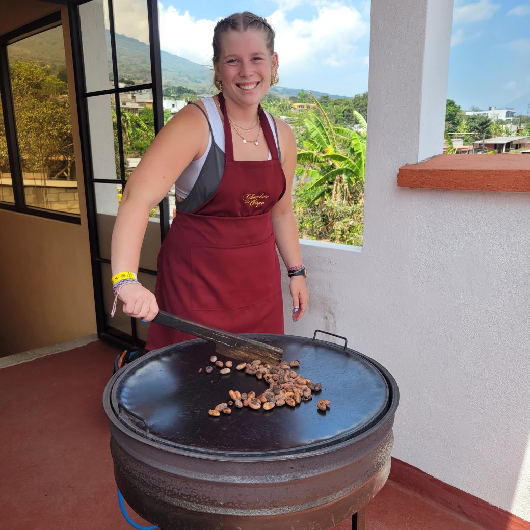 A person standing over a hot roasting pan while wearing an apron.