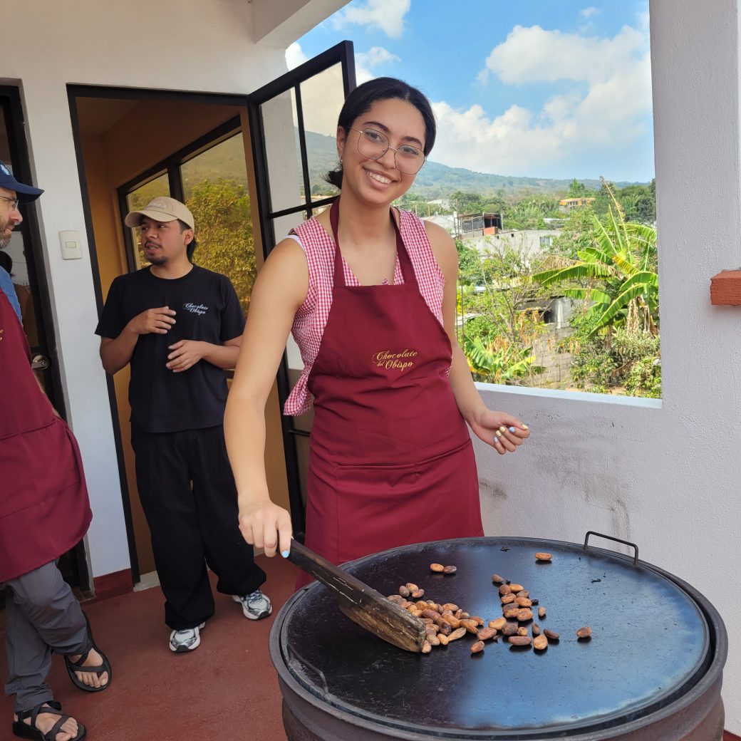 A person standing over a hot roasting pan while wearing an apron.