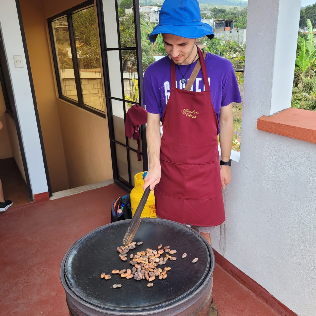 A person standing over a hot roasting pan while wearing an apron.