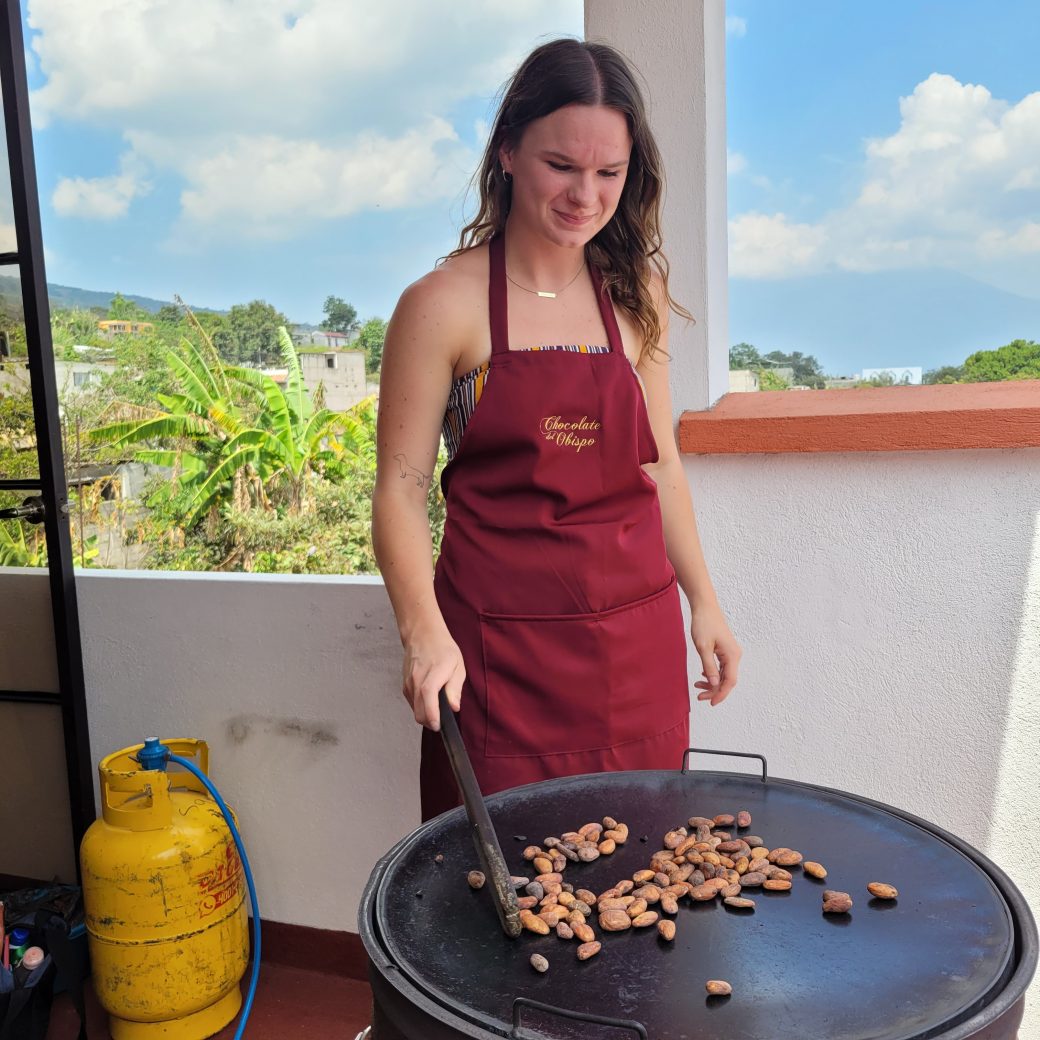 A person standing over a hot roasting pan while wearing an apron.