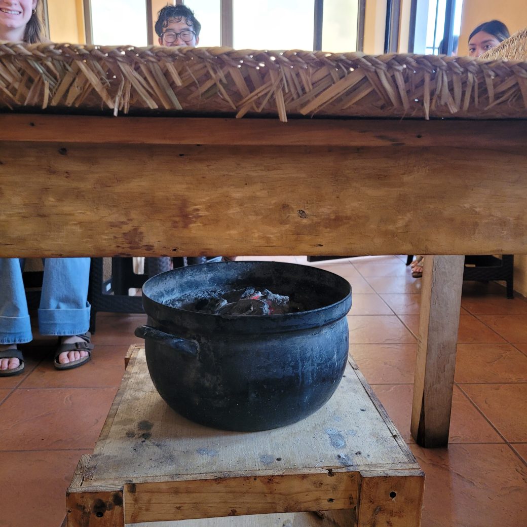A black pots underneath a wooden table.