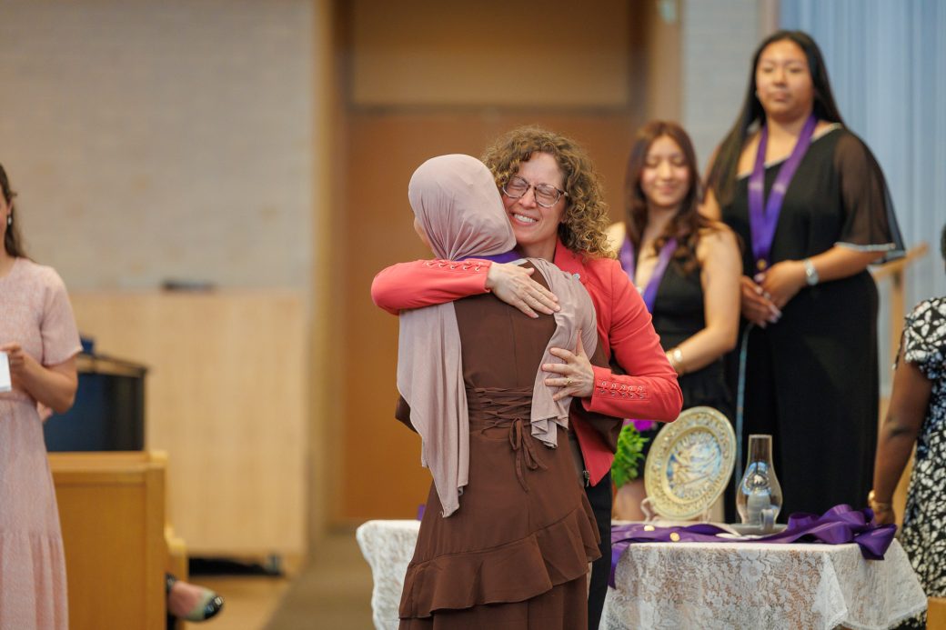 Undergraduate receiving hug after pinning
