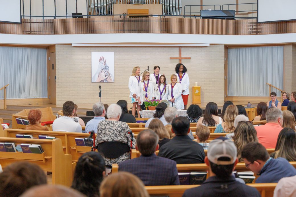 MSN graduates standing before crowd in Goshen College church chapel after receiving pins