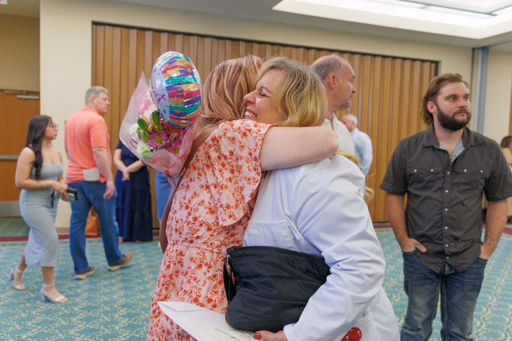 MSN graduate hugging friend and holding balloons