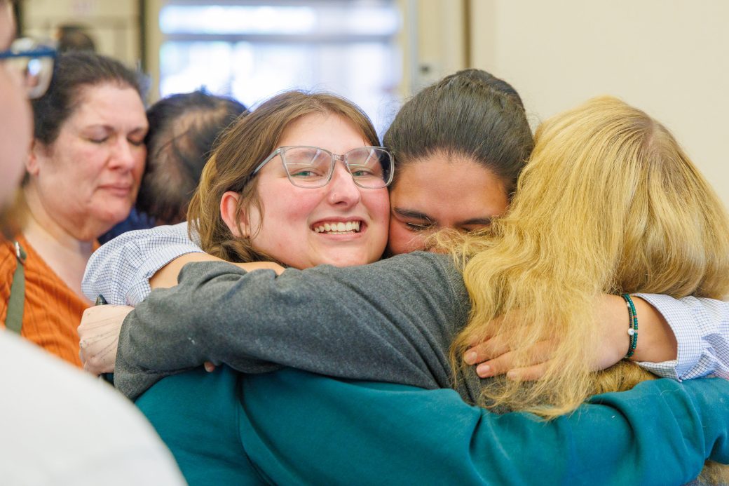 Nursing graduate hugging two friends