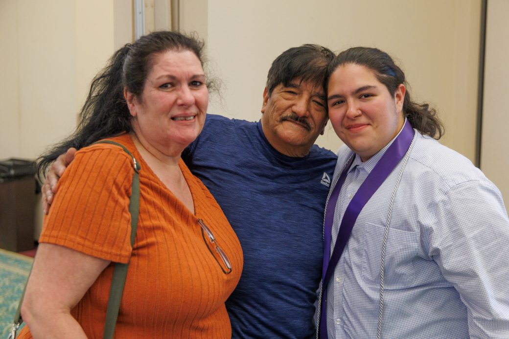 Nursing graduate hugging father and standing next to mother