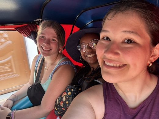 Three people taking a selfie in a red and blue vehicle interior.
