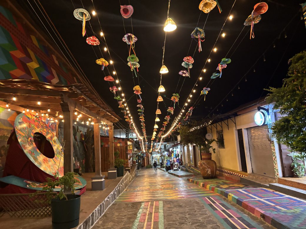 A colorful street at night, lit up with white sparkle lights.