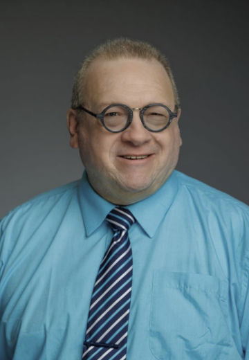 headshot of Tony Krabill in a blue shirt with a gray background