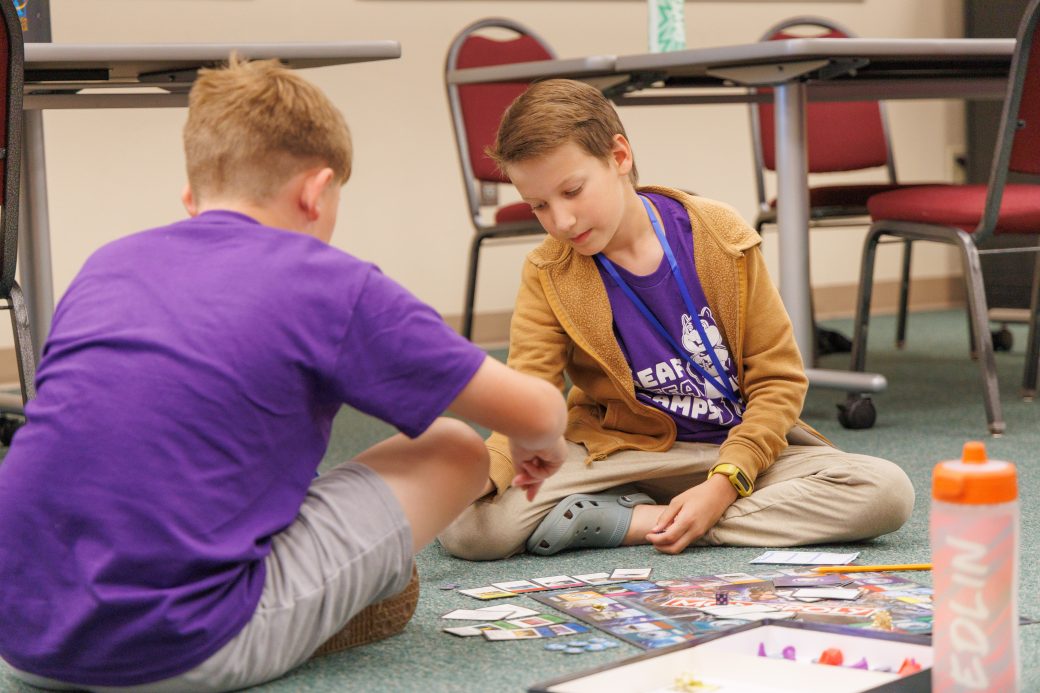 Two kids play board games at summer camp