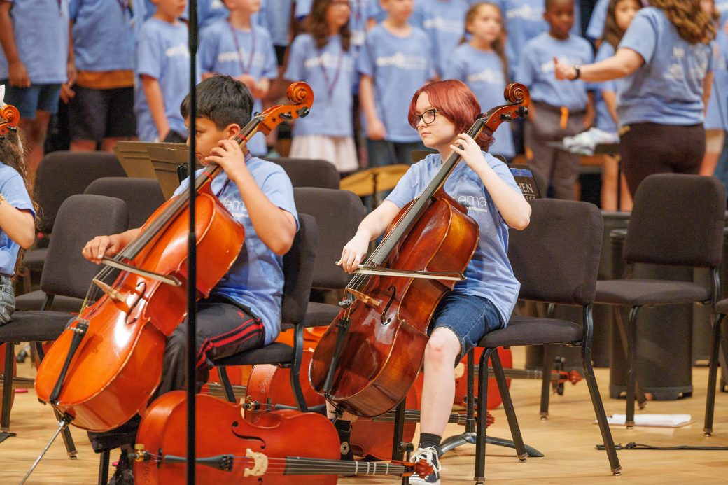 Two students playing cello side by side